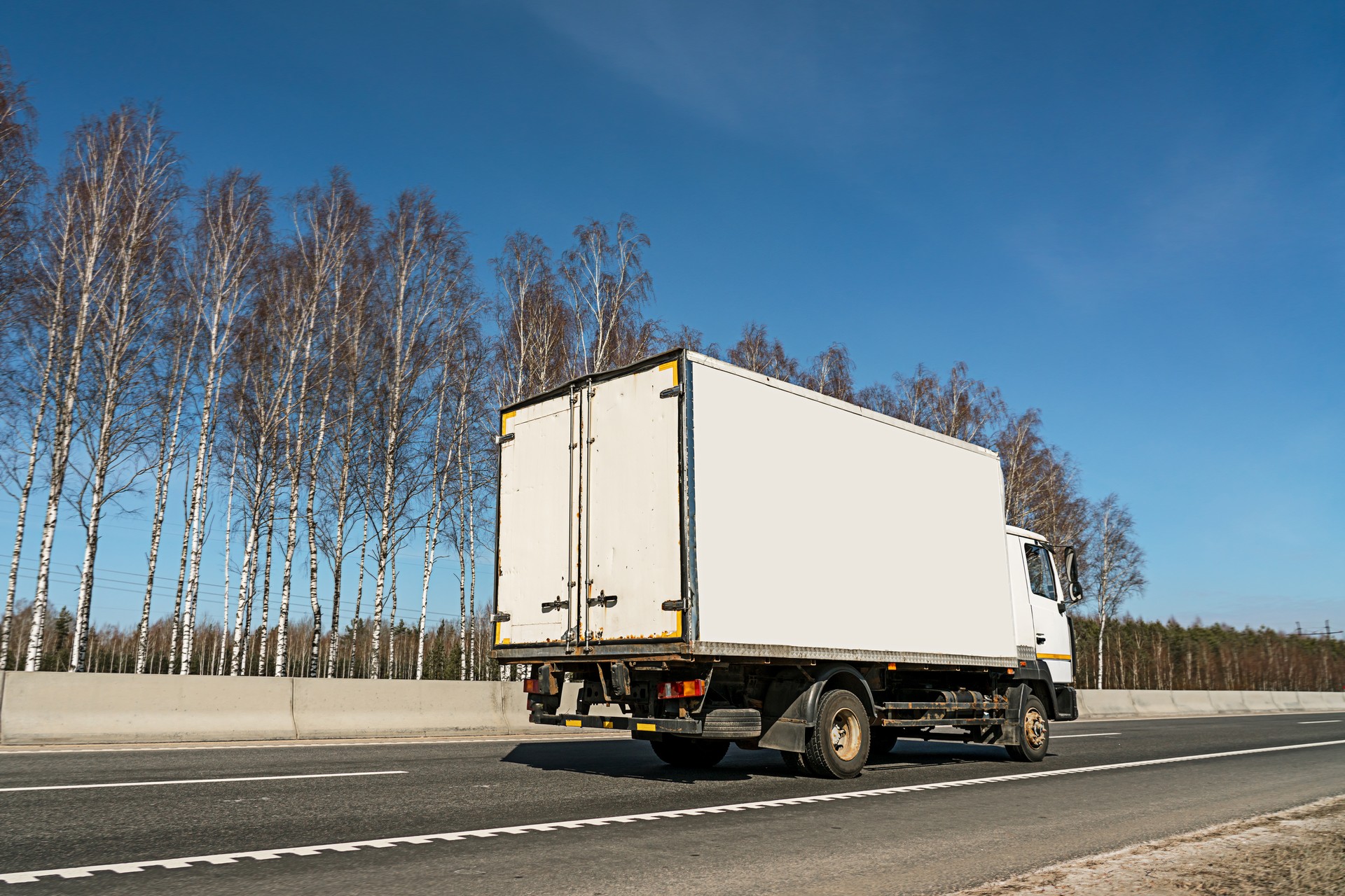 Small delivery truck with empty board for mockup space driving on freeway